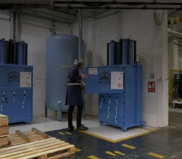 homme dans un environnement de fabrication ouvrant une presse bleue avec le logo Mil-tek